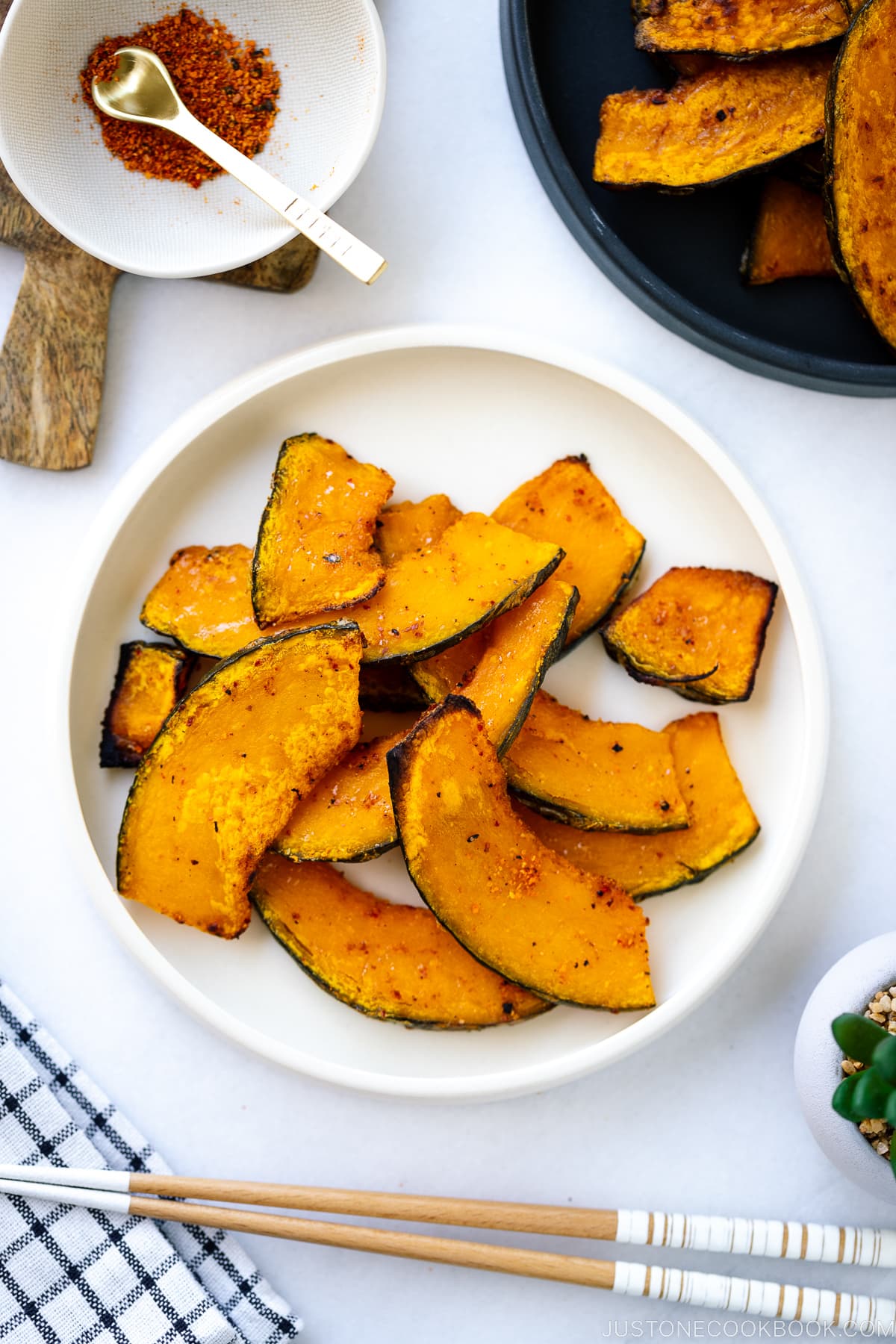 A white round ceramic plate containing roasted kabocha slices.