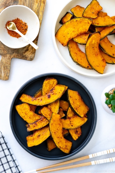 Black and white round ceramic plates containing roasted kabocha slices.