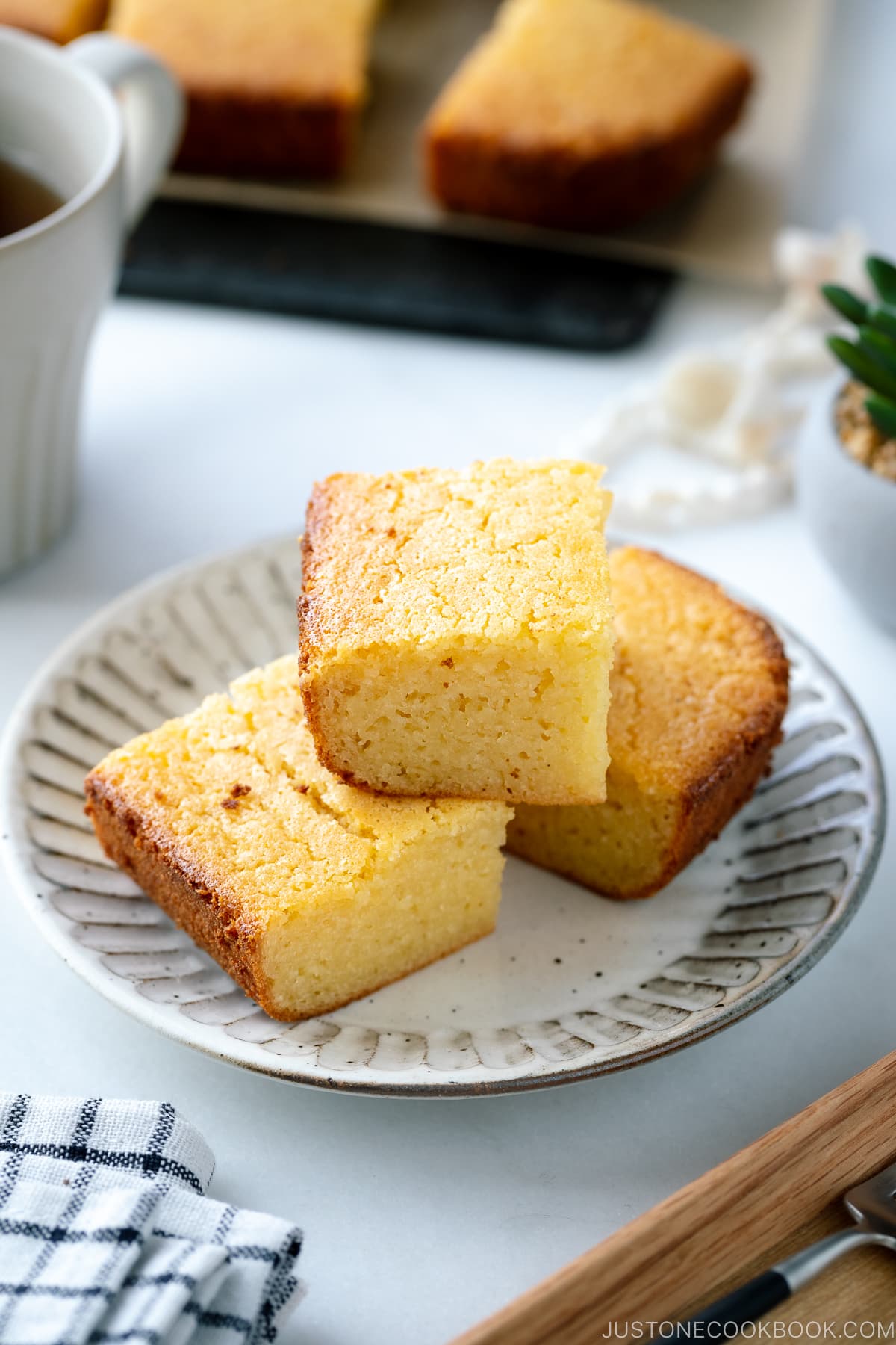 Stacked butter mochi on a white ceramic plate.