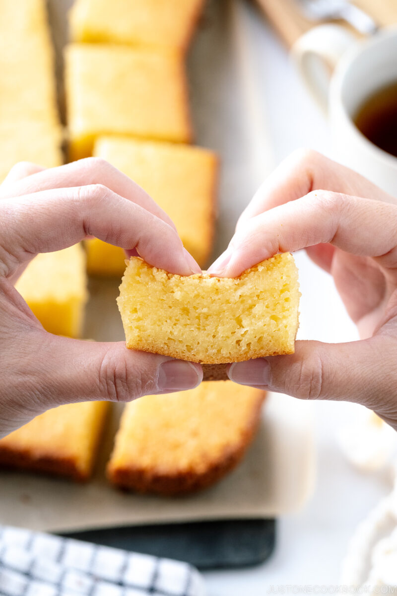 Butter mochi slice is being pulled apart with fingers.