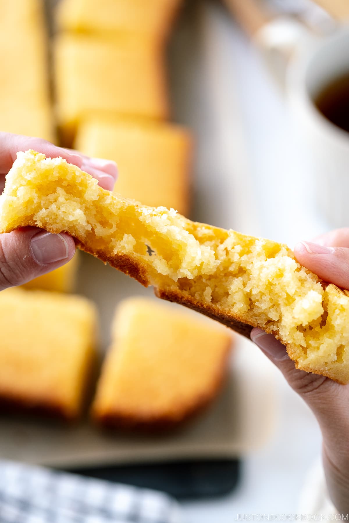 Butter mochi slice is being pulled apart with fingers.