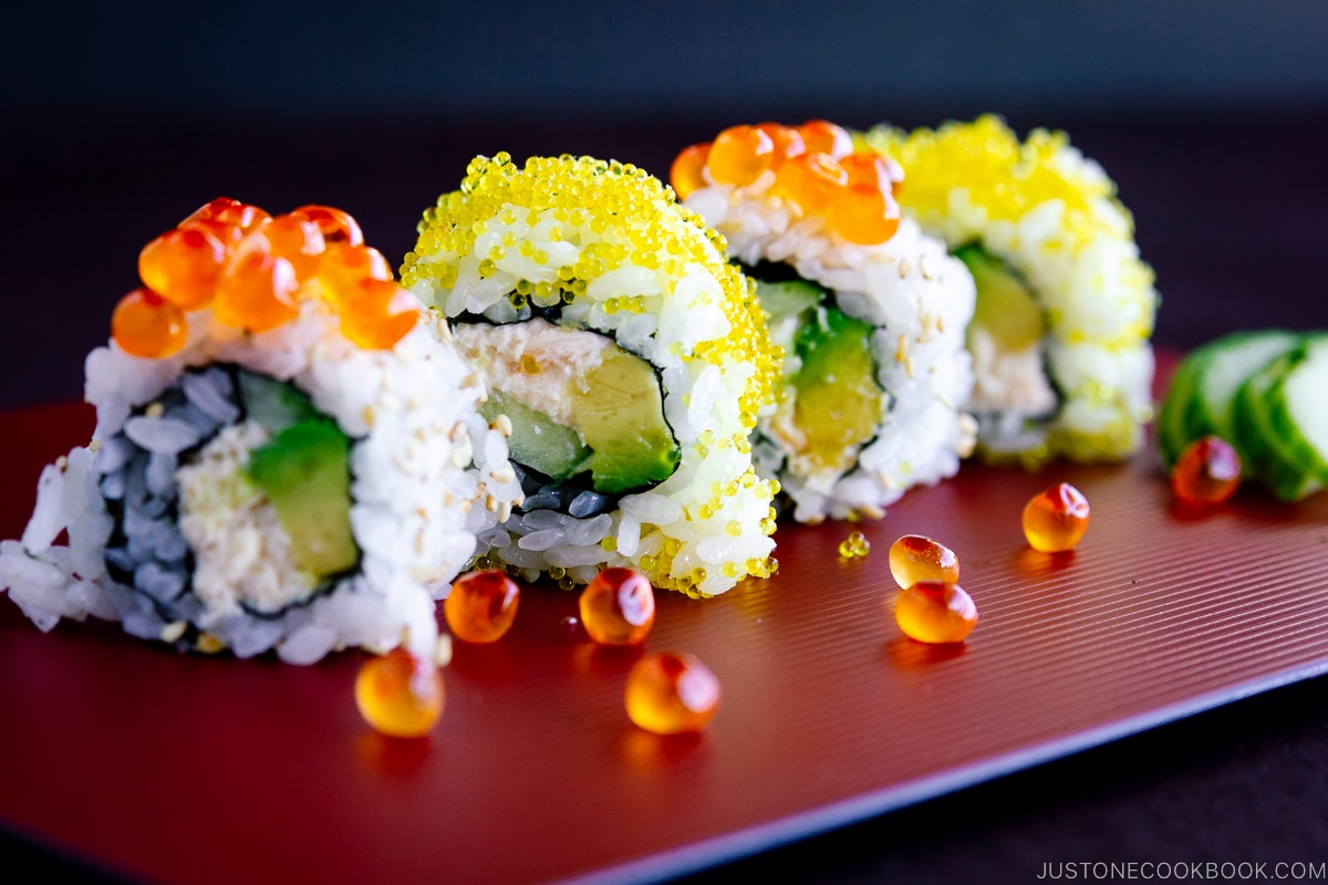 A red platter containing California roll with ikura on top.