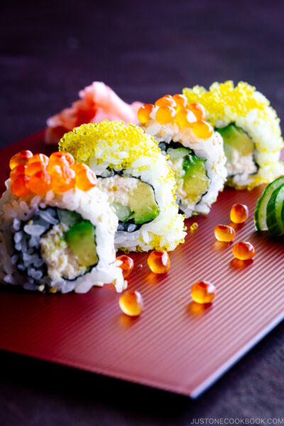 A red platter containing California roll with ikura on top.