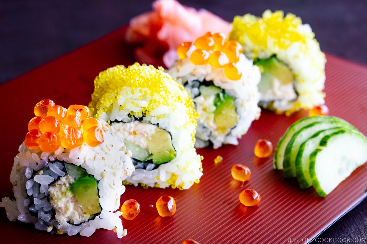 A red platter containing California roll with ikura on top.