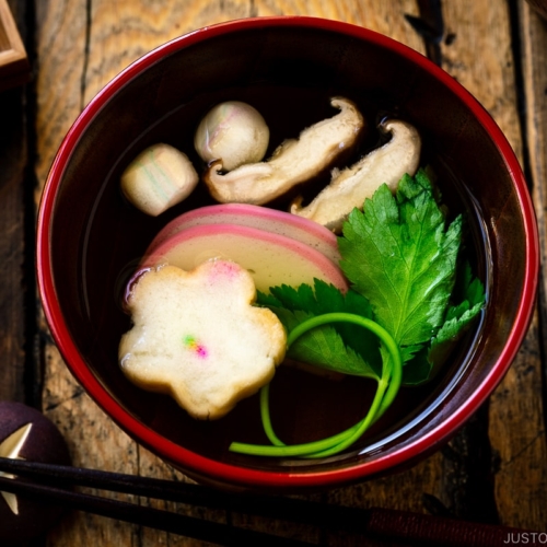 Red Japanese lacquered bowls containing clear soup (Osumashi) with shiitake mushrooms, fu, and mitsuba leaf.