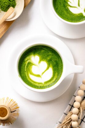 A white cup containing Matcha Latte with a turip latte art.