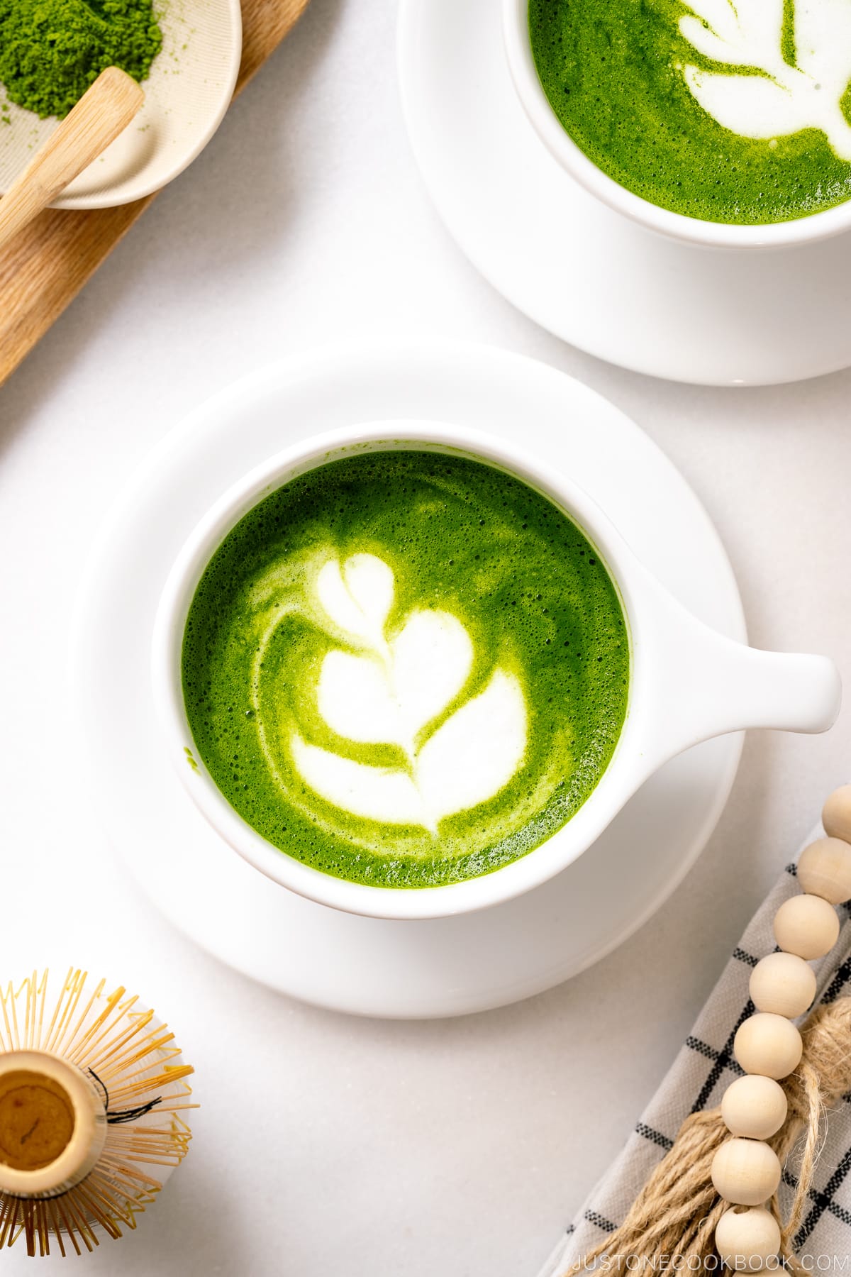 A white cup containing Matcha Latte with a turip latte art.