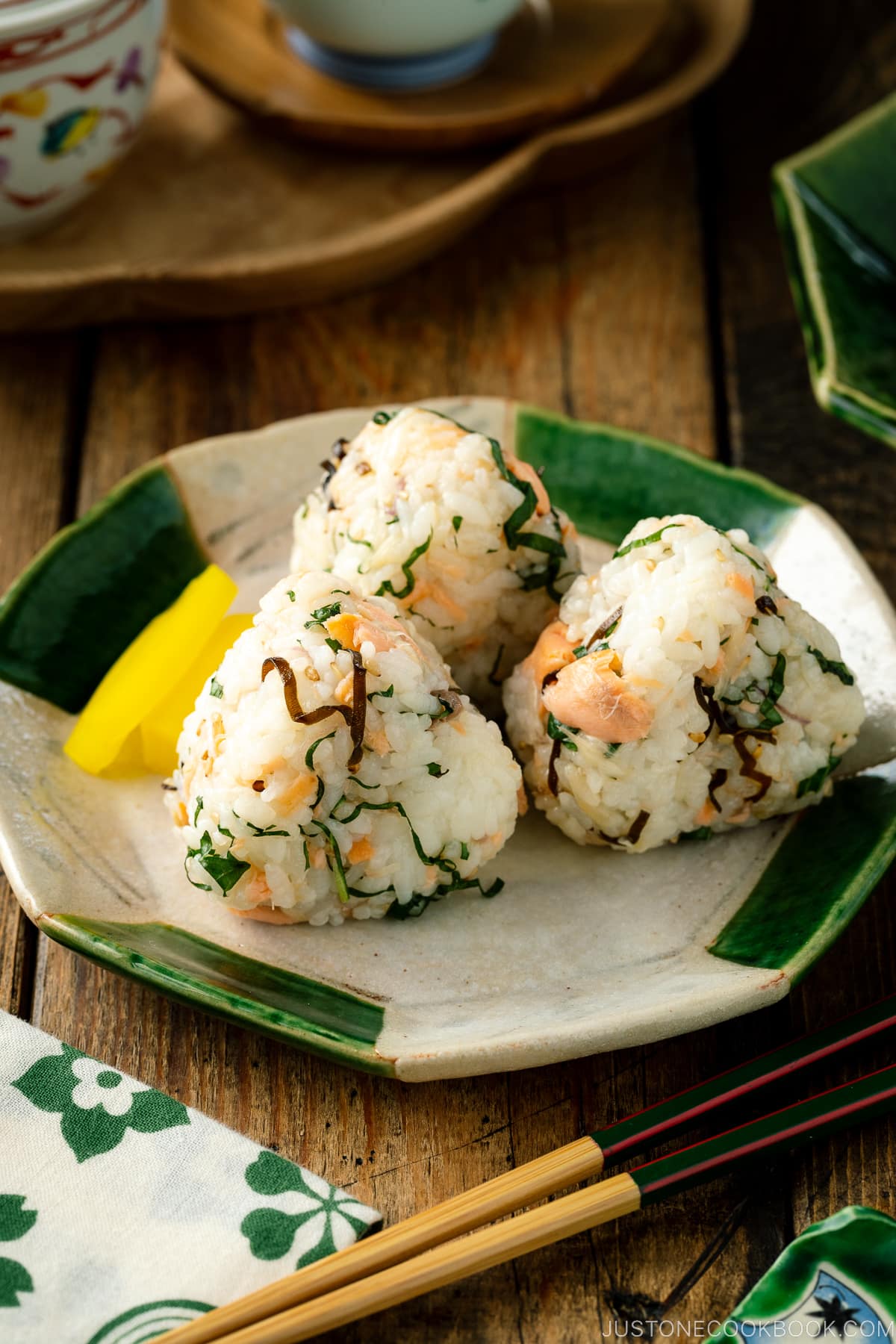 A Japanese ceramic plate containing Salmon and Shio Kombu Onigiri served with daikon pickles.