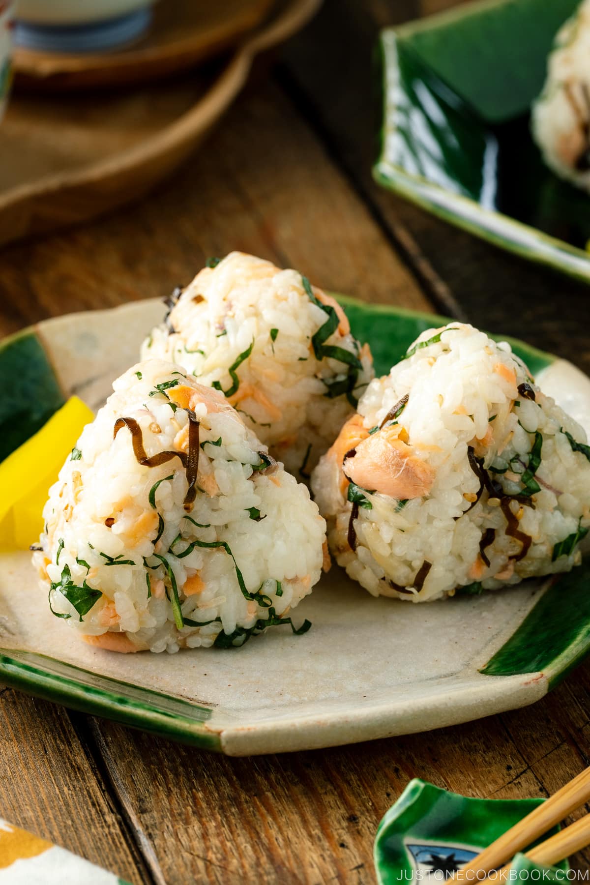 A Japanese ceramic plate containing Salmon and Shio Kombu Onigiri served with daikon pickles.