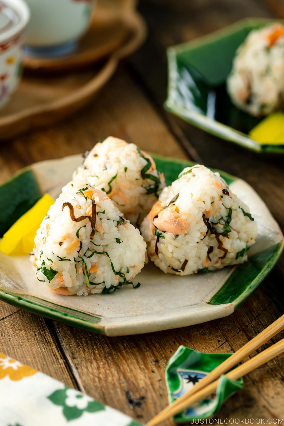 A Japanese ceramic plate containing Salmon and Shio Kombu Onigiri served with daikon pickles.