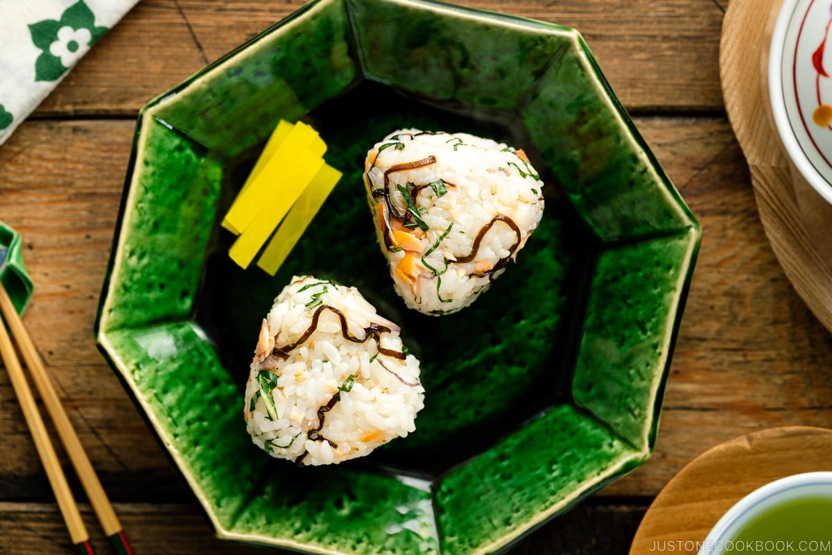 A Japanese ceramic plate containing Salmon and Shio Kombu Onigiri served with daikon pickles.