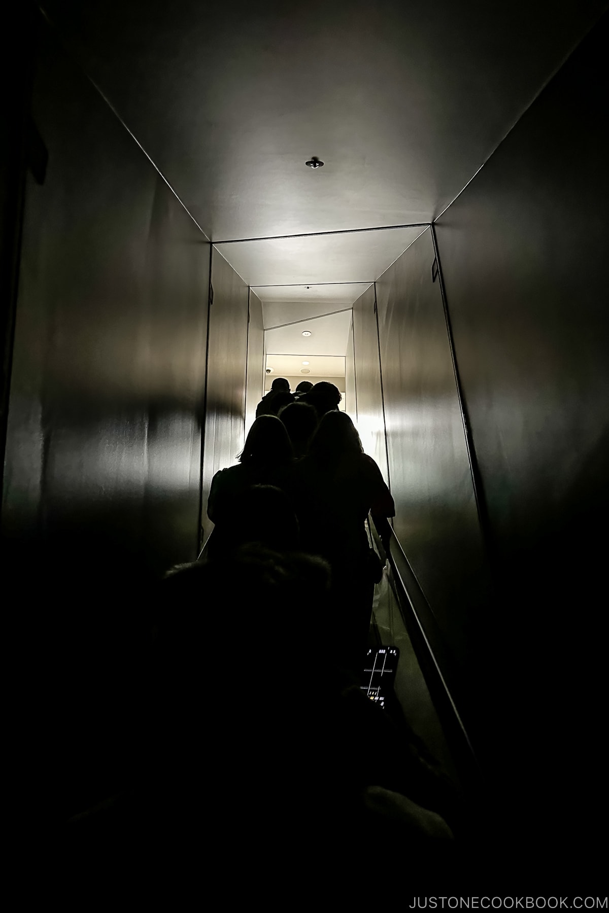 escalator surrounded by black walls and ceiling