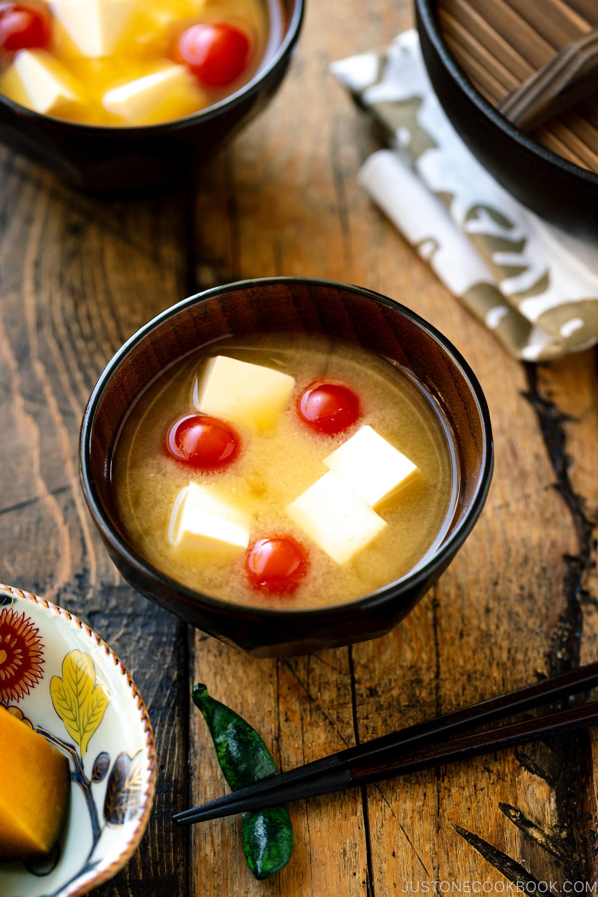 A Japanese wooden bowl containing Tomato and Tofu Miso Soup.