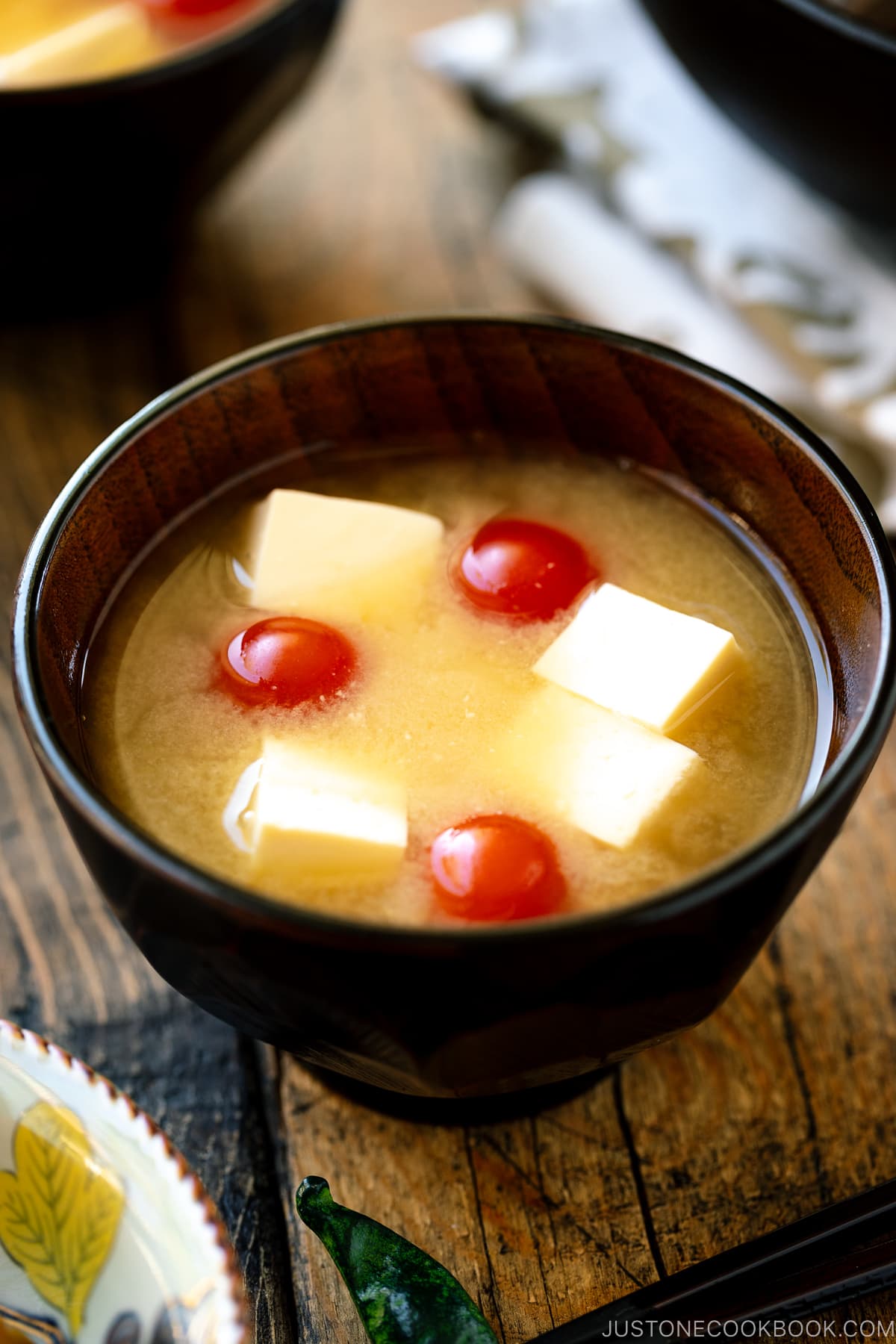 A Japanese wooden bowl containing Tomato and Tofu Miso Soup.