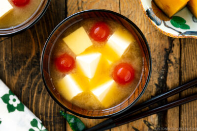 A Japanese wooden bowl containing Tomato and Tofu Miso Soup.