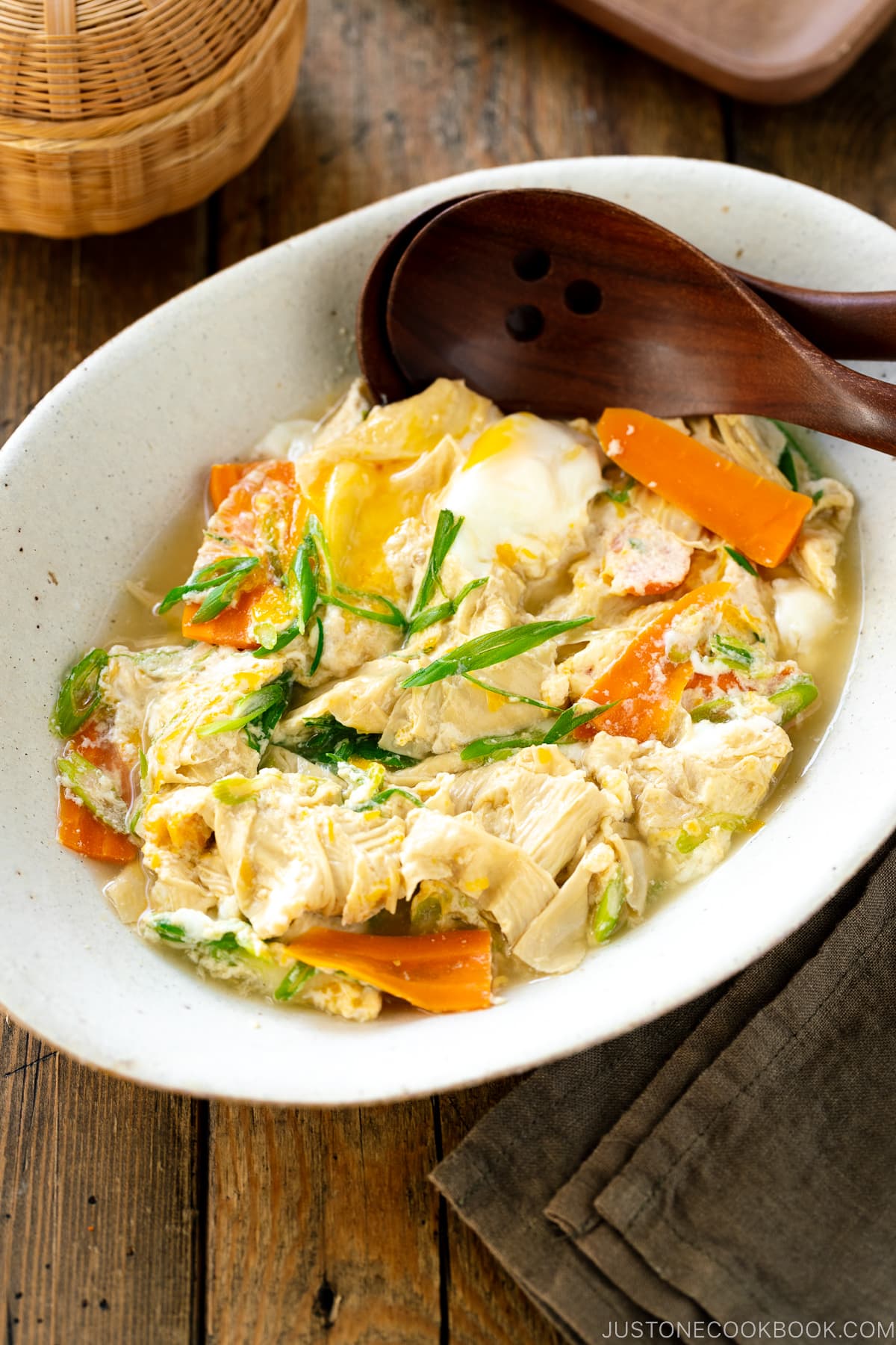 A white ceramic bowl contaiing Yuba Tamagotoji (Simmered Tofu Skin with Soft Scrambled Eggs).