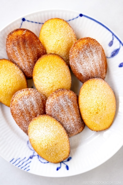 A Royal Copenhagen plate containing Madeleines dusted with powdered sugar.