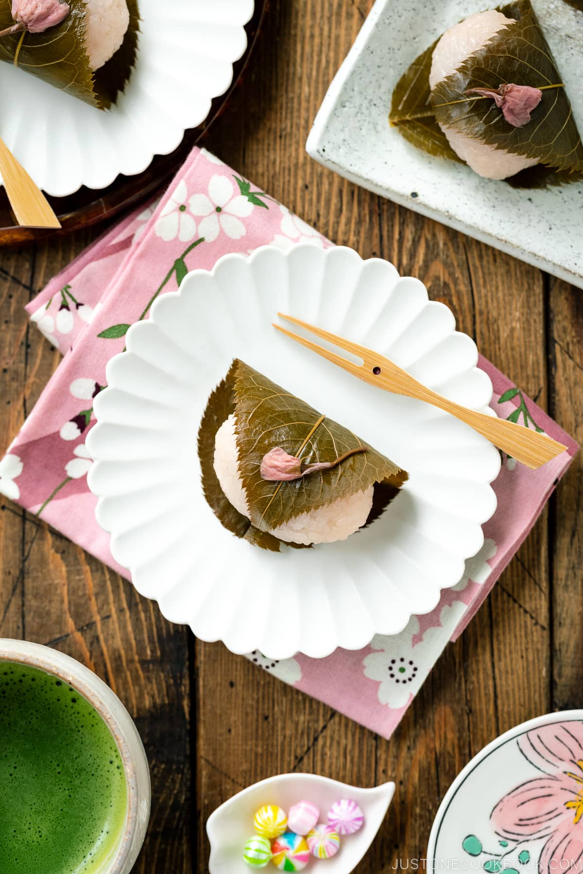 A round fluted plate containing sakura mochi served with matcha tea.