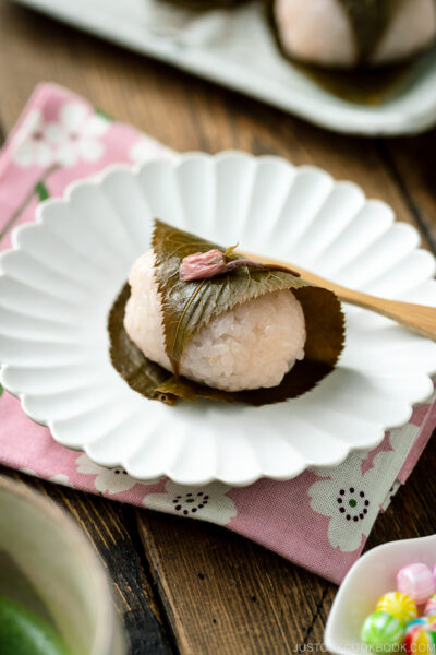 A round fluted plate containing sakura mochi served with matcha tea.