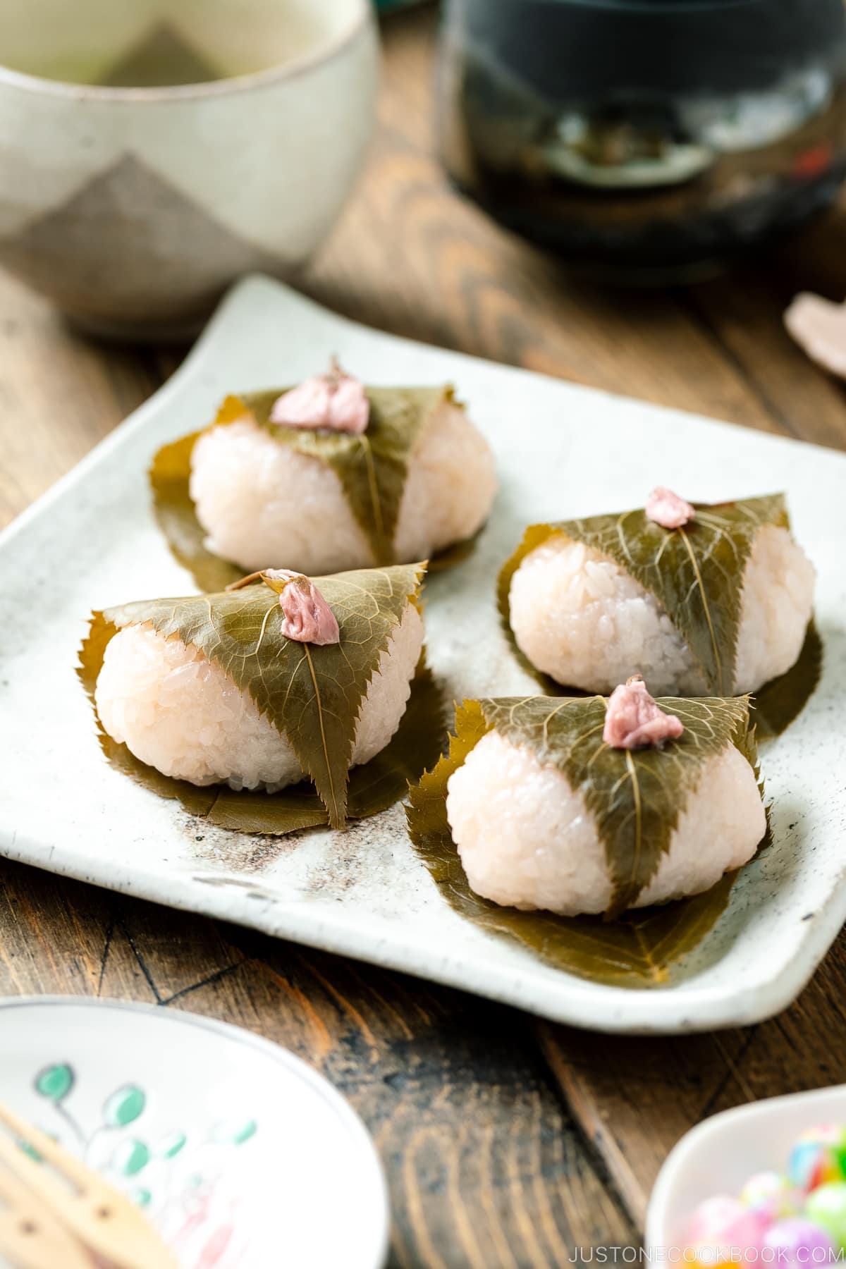 A white square plate containing sakura mochi.