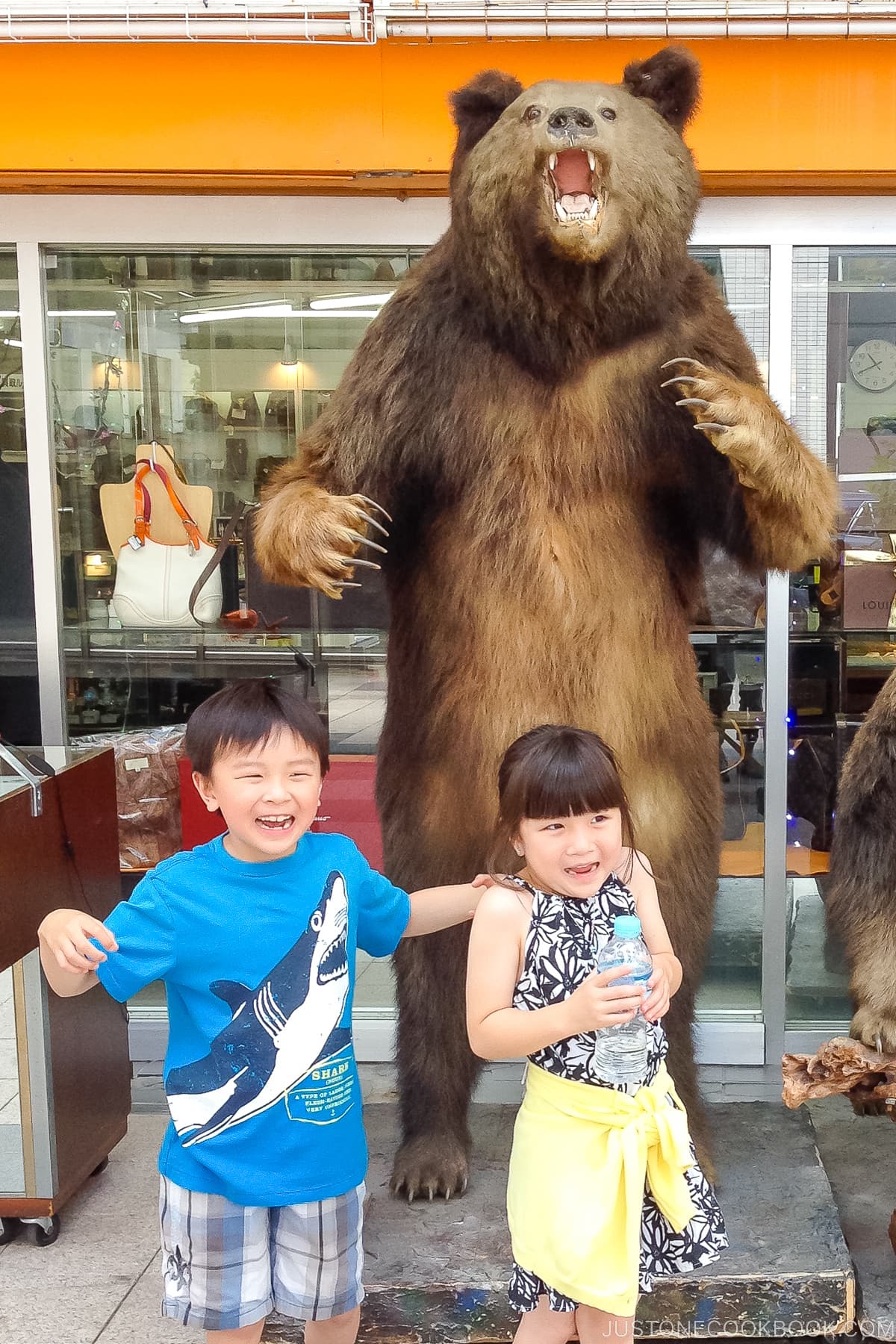 a girl and a boy in front of a stuffed bear