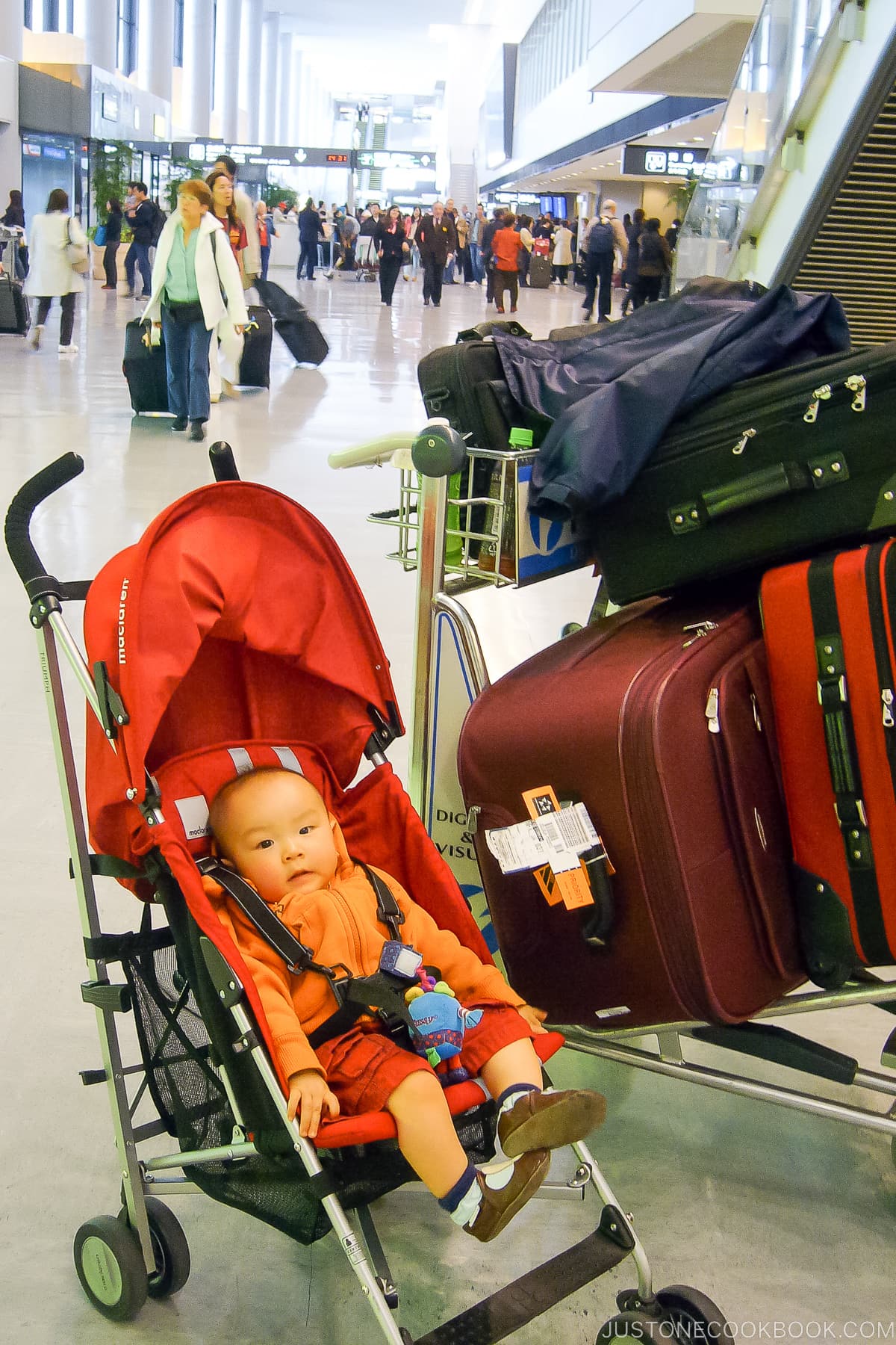 baby in stroller next to luggages