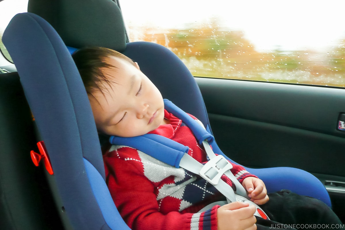 a boy sleeping in a car seat