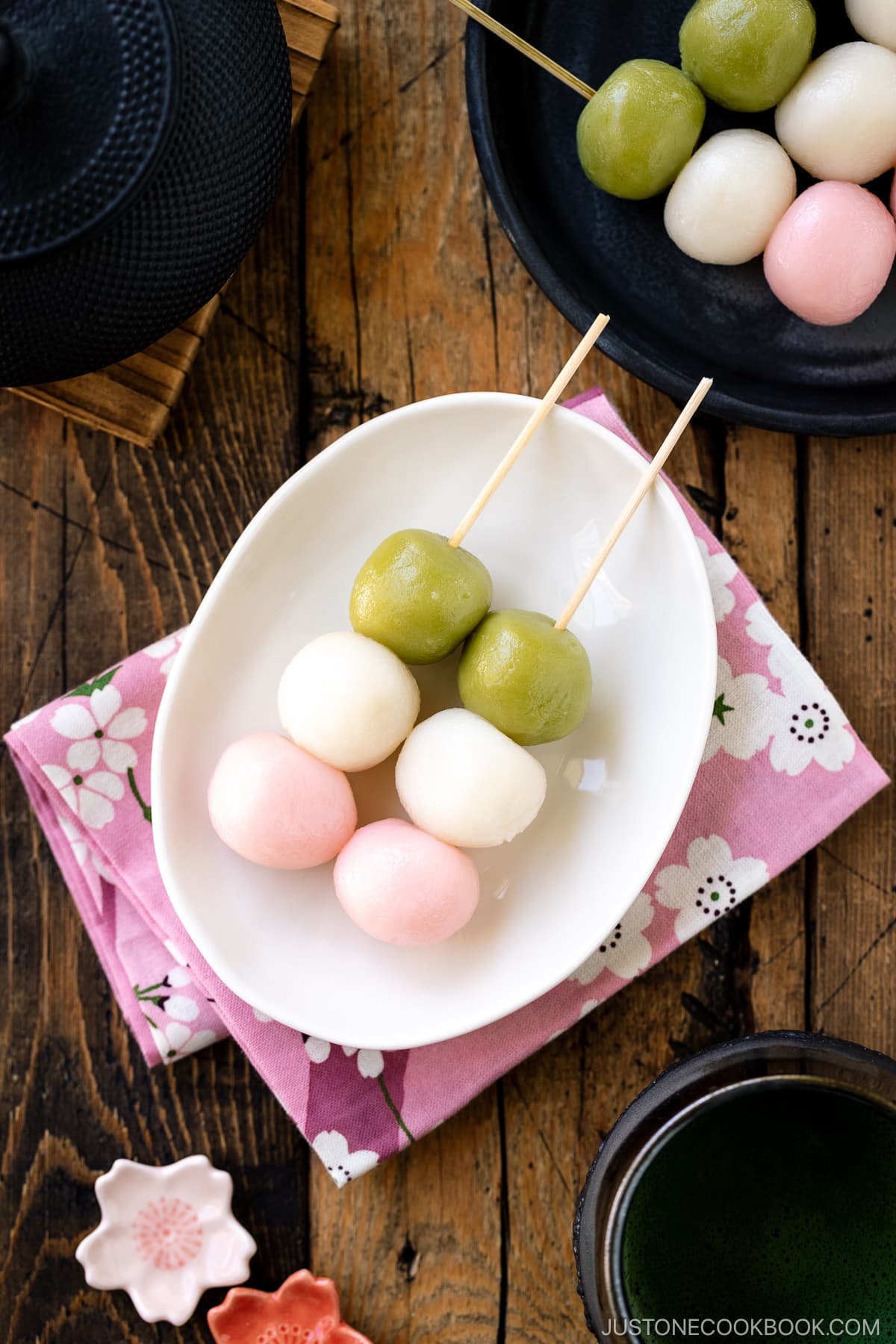 A white oval plate containing two Hanami Dango, served with matcha green tea.