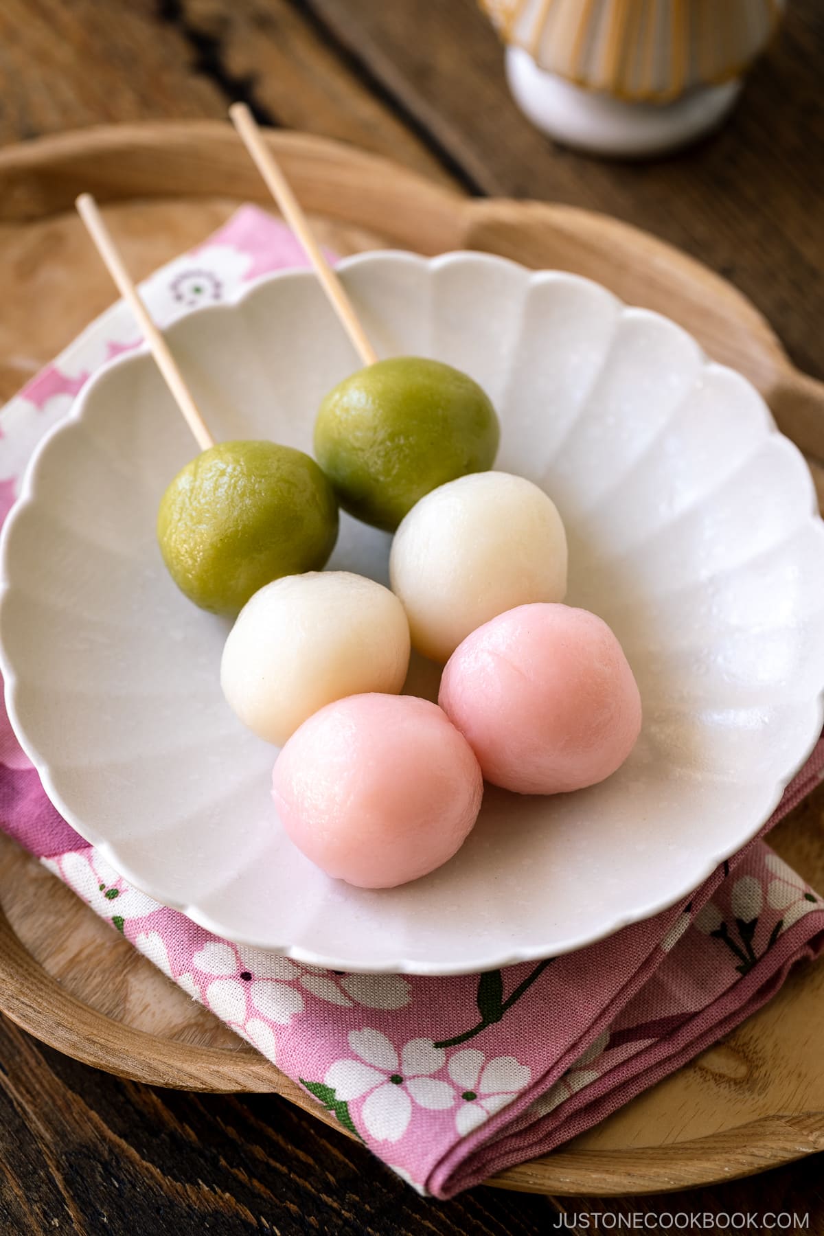 A white fluted round plate containing two Hanami Dango, served with matcha green tea.