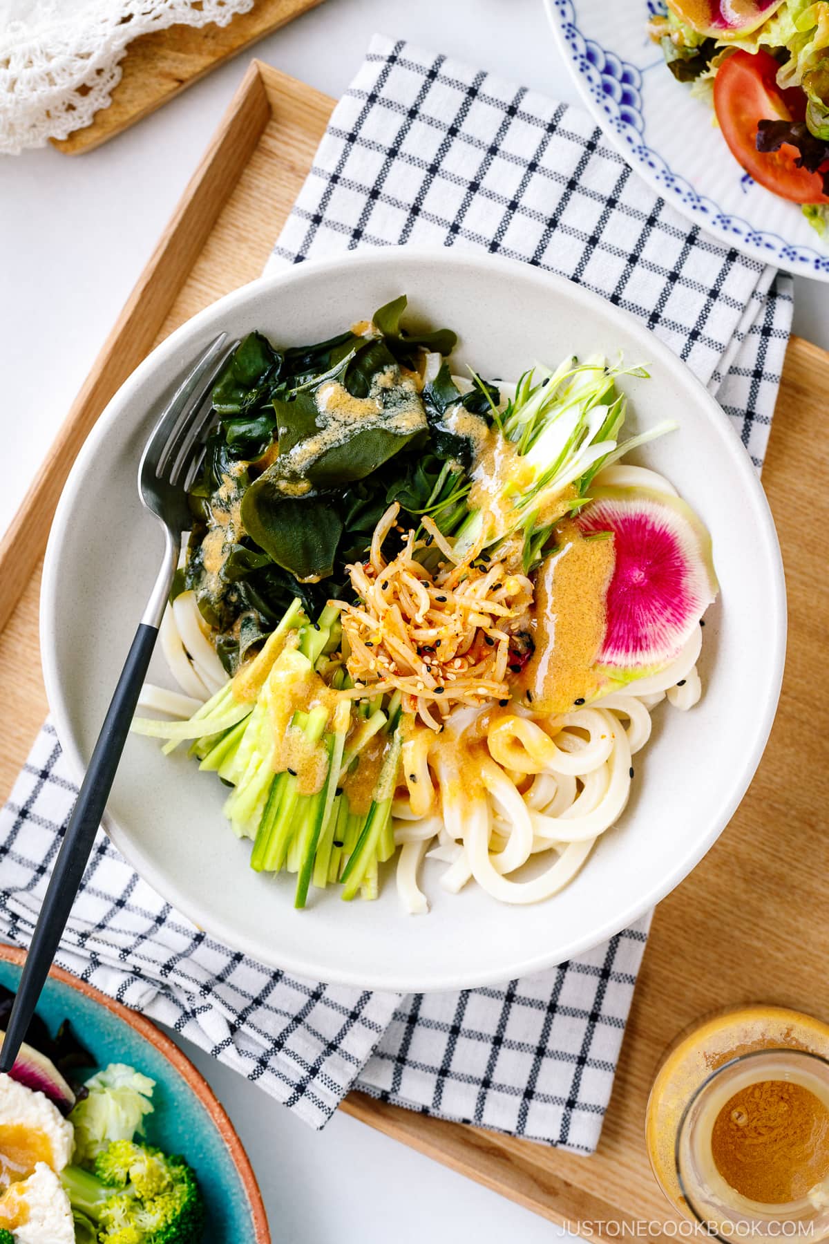 A ceramic plate containing udon noodles, wakame seaweed, and julienned cucumber topped with homemade Miso Dressing.
