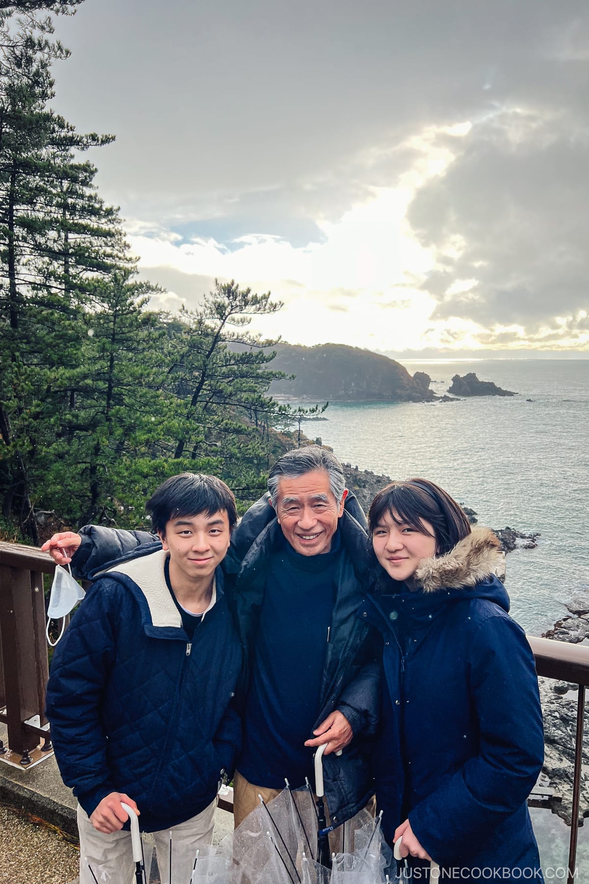 two teen with an older man standing next to ocean