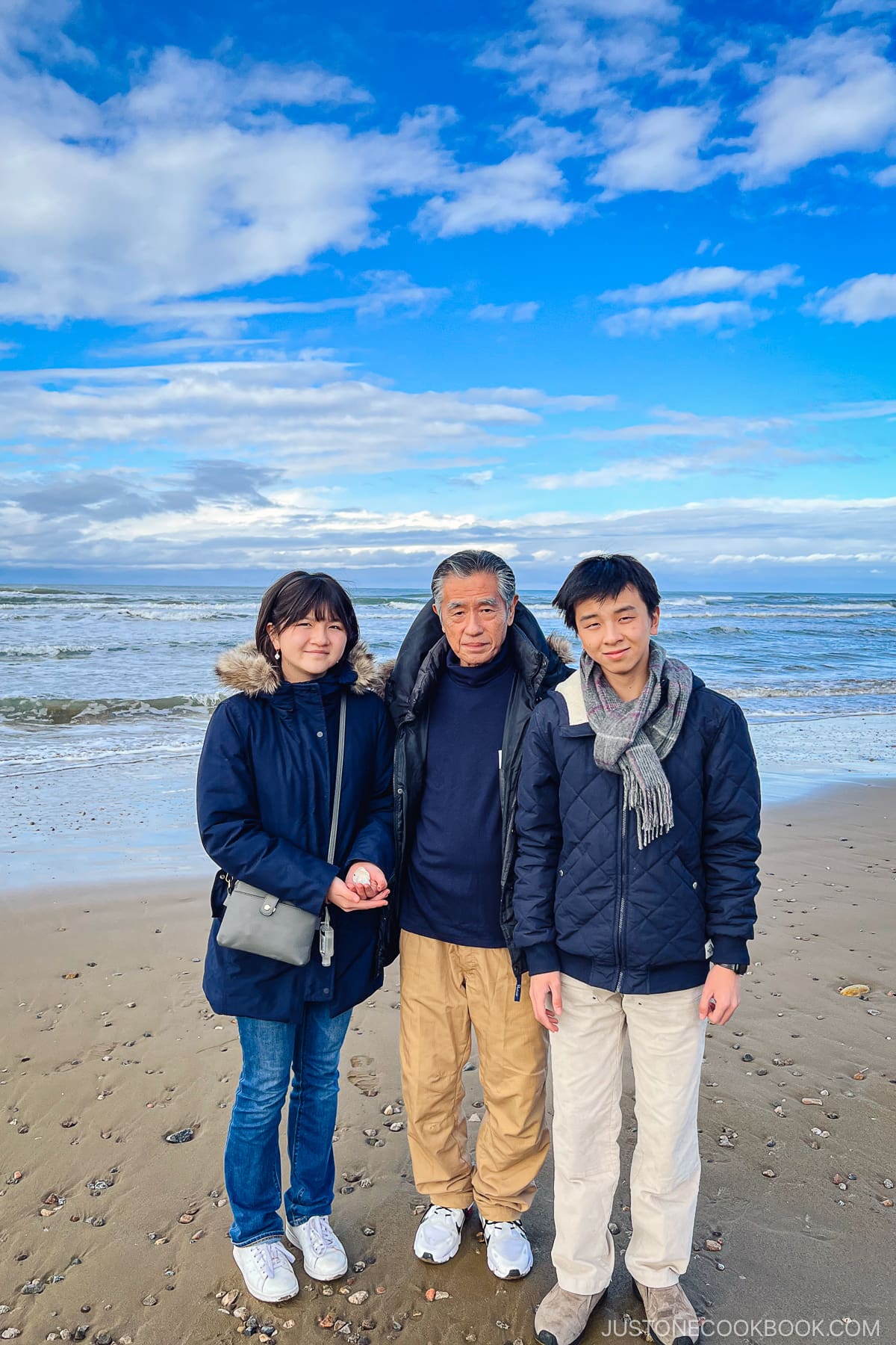 two teens standing next to an older man on the beach