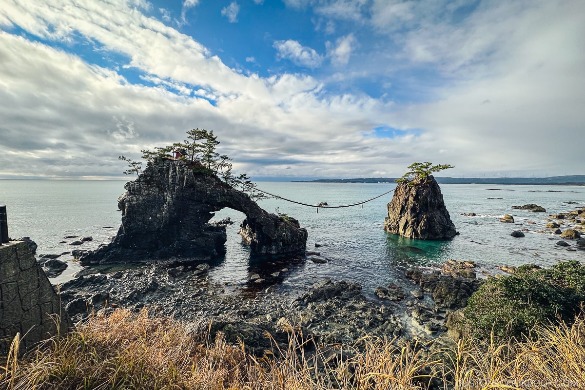 a rope connecting two large rocks formation protruding from ocean