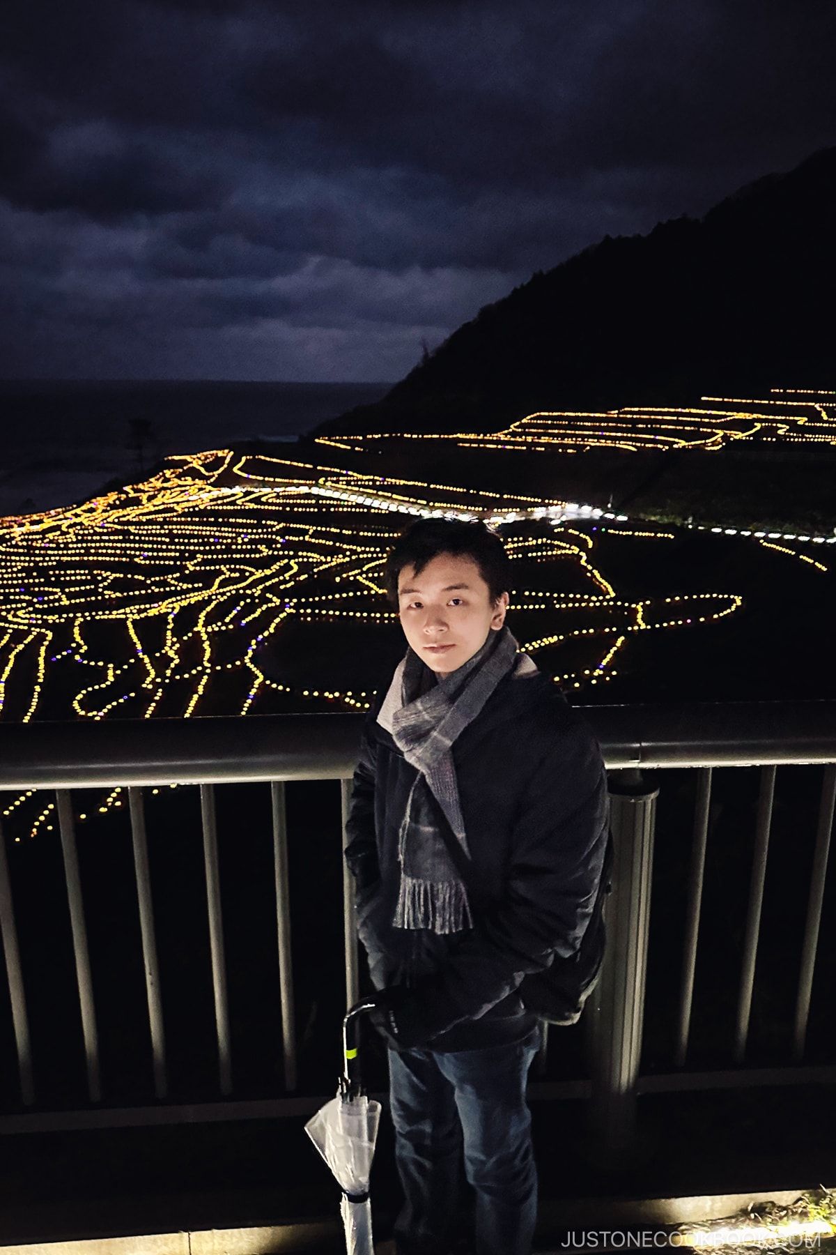 teenager visiting Shiroyone Senmaida Rice Terraces lit up at night