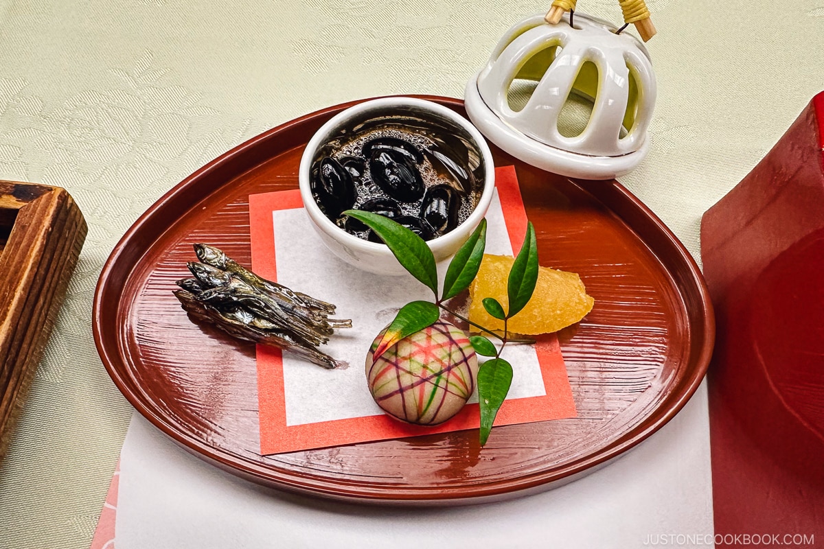 black bean and small dishes served on a red lacquer plate