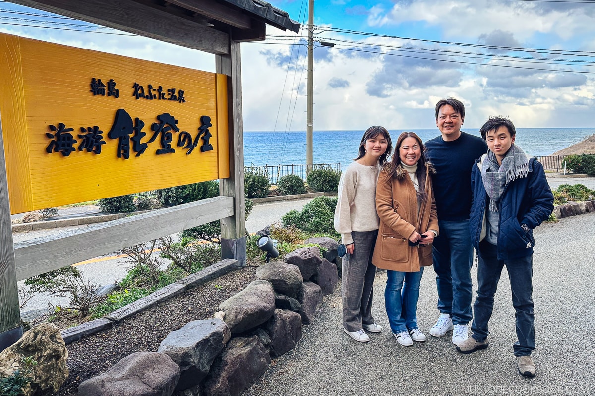 four people standing next to a sign