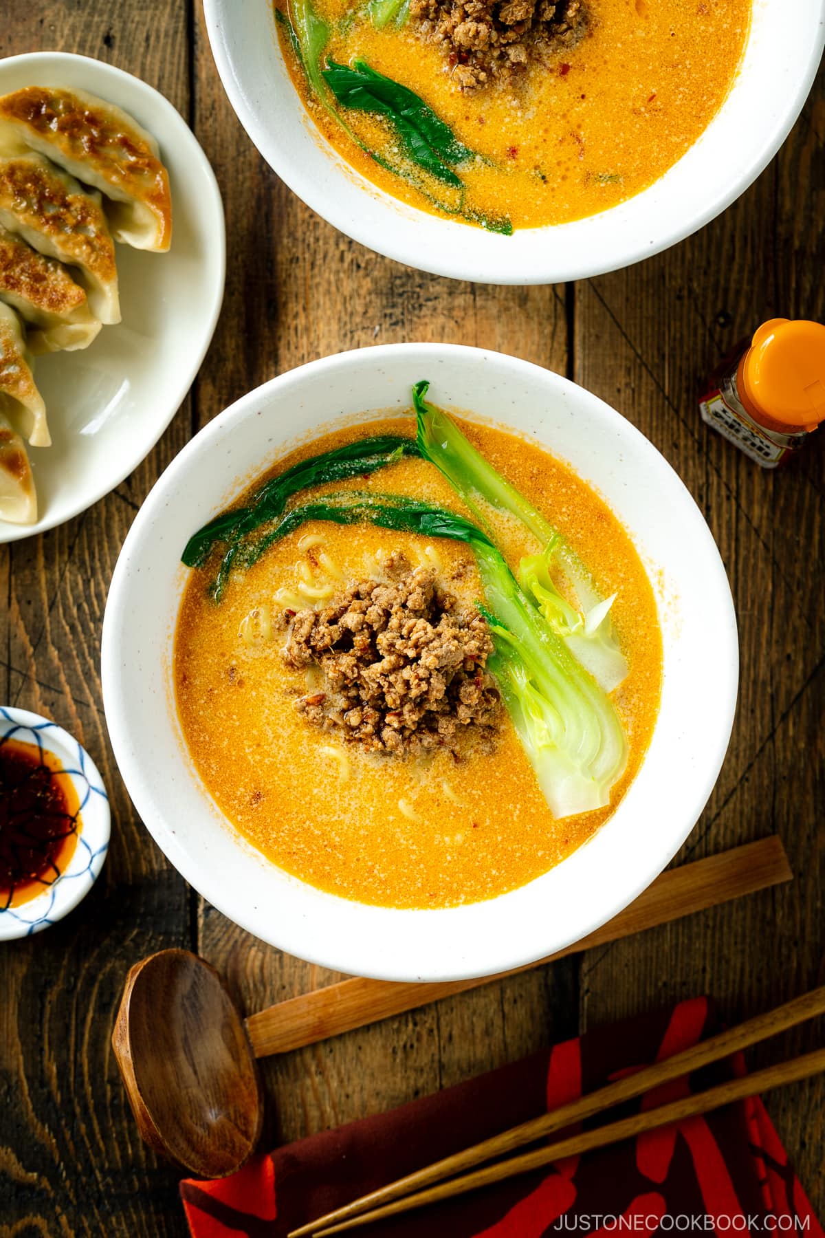 A white bowl containing Tan Tan Ramen (Tantanmen) which consists of ramen noodles and spicy creamy sesame soup, topped with savory ground pork mixture and blanched bok choy.