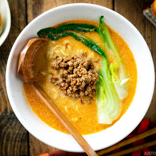 A white bowl containing Tan Tan Ramen (Tantanmen) which consists of ramen noodles and spicy creamy sesame soup, topped with savory ground pork mixture and blanched bok choy.