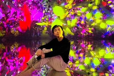 a boy sitting on mirrored floor surrounded by with floral projections