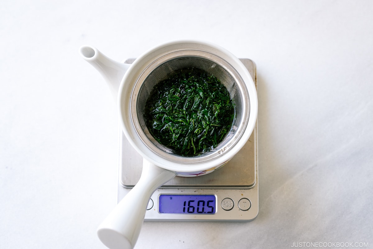 green tea leaves seeping in a teapot on a scale
