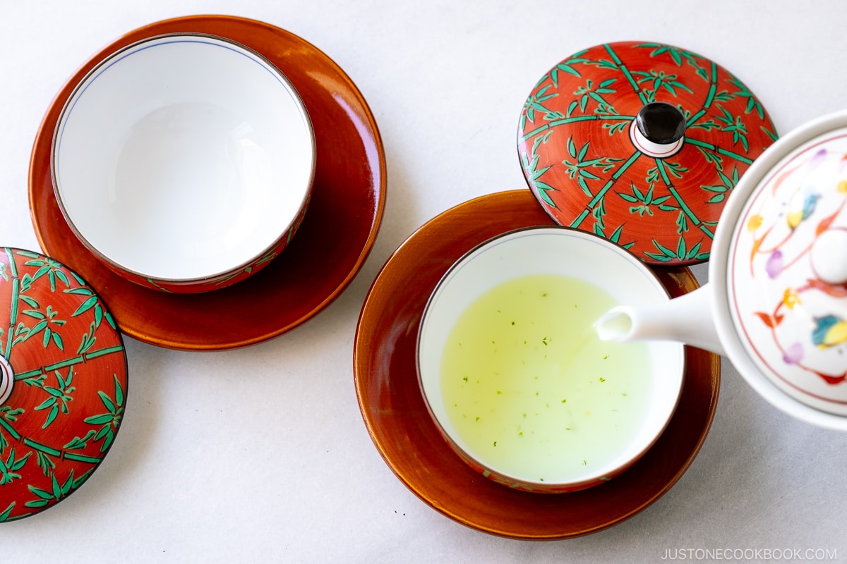 green tea being poured into a red teacup