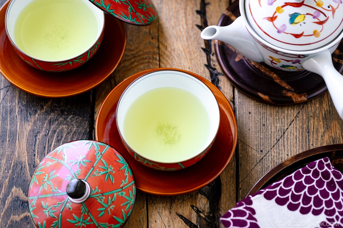 2 red teacup on a wooden table with a teapot