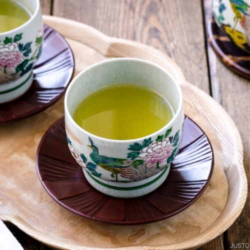 green tea in 2 ceramic teacups on a wooden table