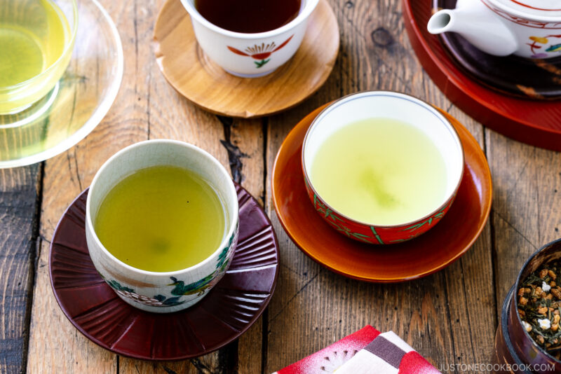 an assortment of green tea in teacups on a wooden table