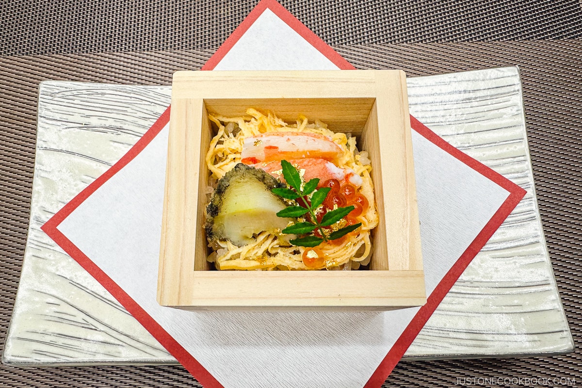 abalone and seafood on top of eggs and rice in a wooden box