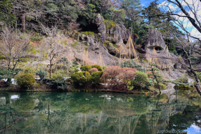 a mountain with stone caves in back of a pond