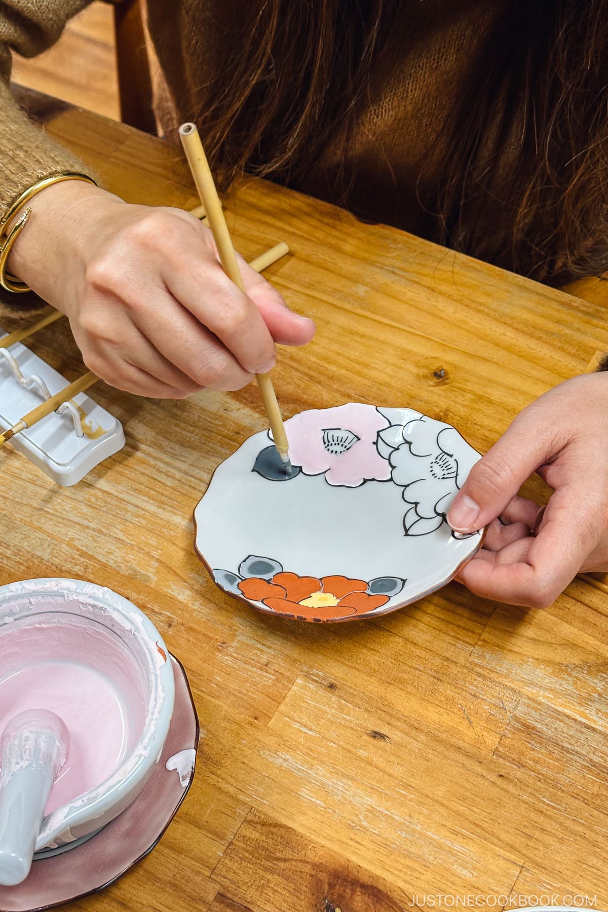 a person painting on a porcelain plate