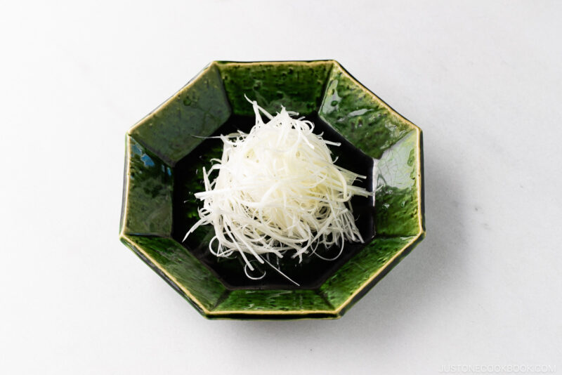 A green plate containing Shiraga Negi (Julienned Long Green Onion Garnish).