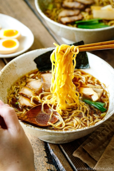 A ramen bowl containing shoyu ramen topped with chashu, seasoned bamboo shoots, green onion, and nori.