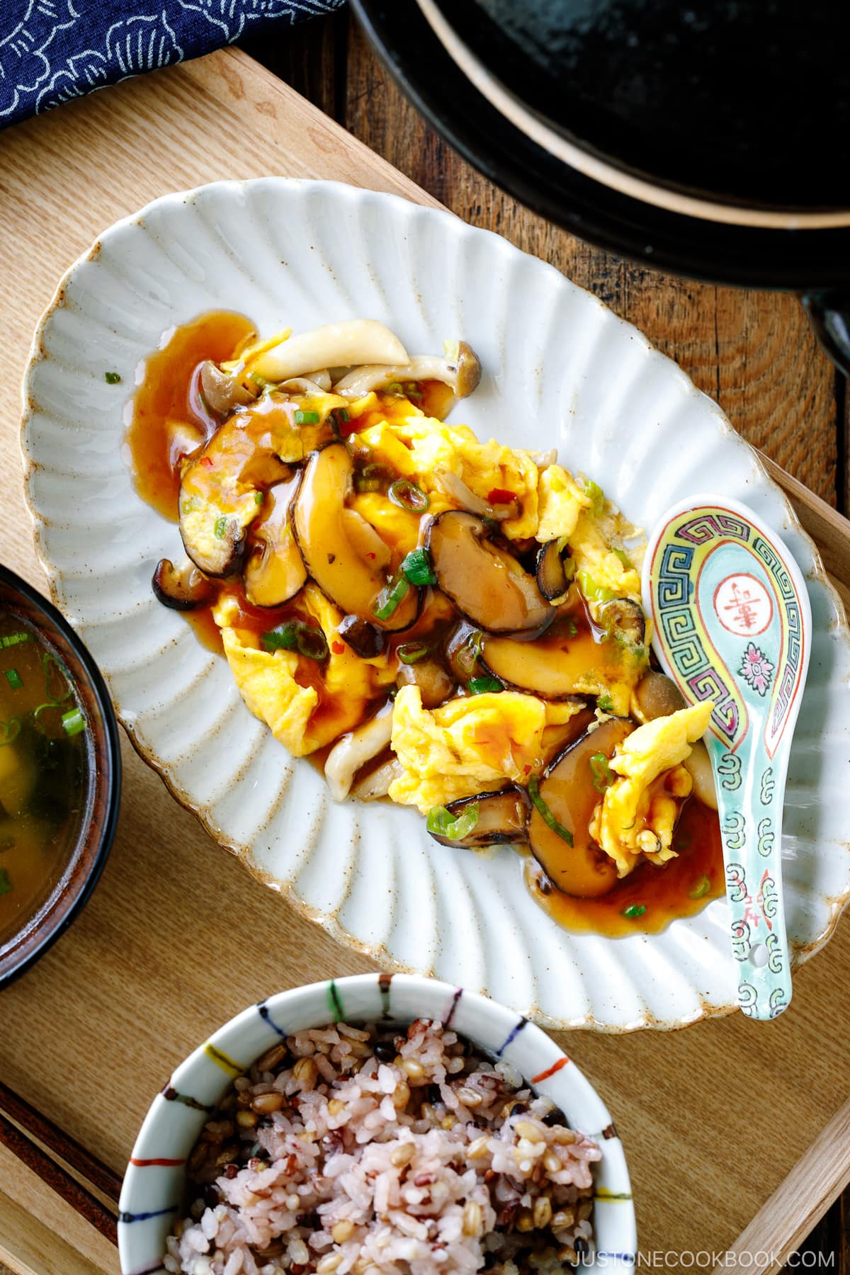 A fluted oval shape containing stir-fried mushrooms and eggs drizzled with ankake sauce.